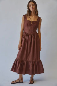 Woman wearing a brown dress against a plain background