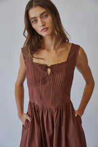 Woman wearing a brown dress against a plain background