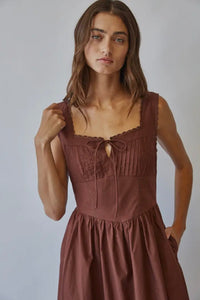 Woman wearing a brown dress against a plain background