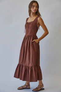 Woman wearing a brown dress against a plain background
