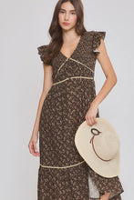 Load image into Gallery viewer, A woman modeling a brown floral midi dress with ruffled cap sleeves and cream trim, holding a beige straw hat against a light gray studio background.