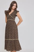 Load image into Gallery viewer, A woman modeling a brown floral midi dress with ruffled cap sleeves, a V-neckline, and thin cream trim details, set against a plain light gray studio background.