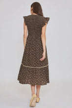 Load image into Gallery viewer, A woman viewed from the back wearing a knee-length brown dress with a small floral print and ruffled cap sleeves, paired with beige heels, against a light gray studio background.