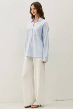 Load image into Gallery viewer, Woman wearing a light blue striped shirt and white pants against a white background