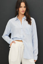 Load image into Gallery viewer, Woman wearing a light blue striped shirt and white pants against a black background