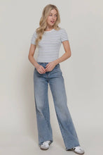 Load image into Gallery viewer, Woman wearing a striped shirt and blue jeans on a plain background