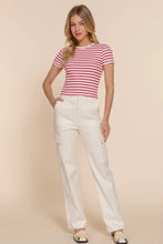 Load image into Gallery viewer, Woman wearing a red and white striped shirt and white pants on a beige background