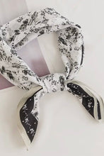 Load image into Gallery viewer, Black and white patterned scarf tied around a white candle on a light gray background