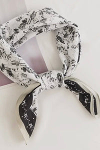Black and white patterned scarf tied around a white candle on a light gray background