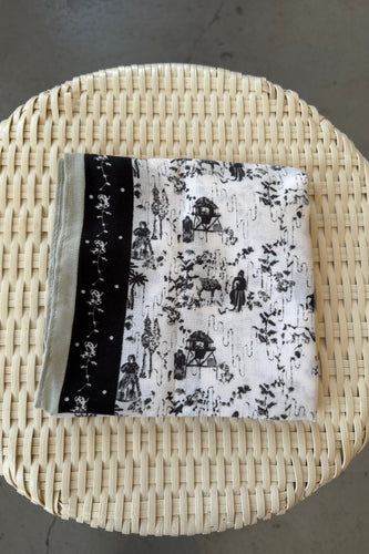 Black and white patterned fabric in a woven basket on a gray surface