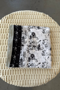 Black and white patterned fabric in a woven basket on a gray surface