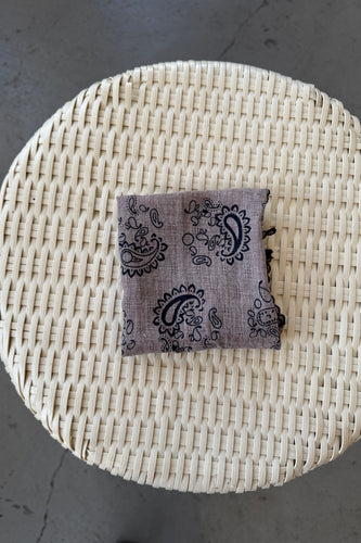 Woven basket with a patterned pouch on a gray surface