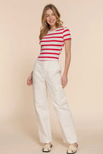 Load image into Gallery viewer, Woman wearing a red and white striped shirt and white pants on a beige background