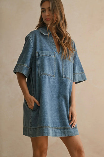 Woman wearing a denim dress against a beige background