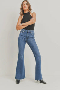 Woman wearing blue flared jeans and a black top on a plain background