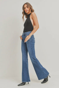Woman wearing blue flared jeans and a black top on a white background
