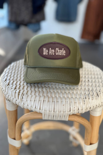 Green cap with 'We Are Charlie' text on a wicker stool