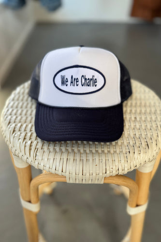 Trucker hat with 'We Are Charlie' text on a woven stool.