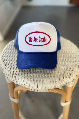 Trucker hat with 'We Are Charlie' text on a wicker stool