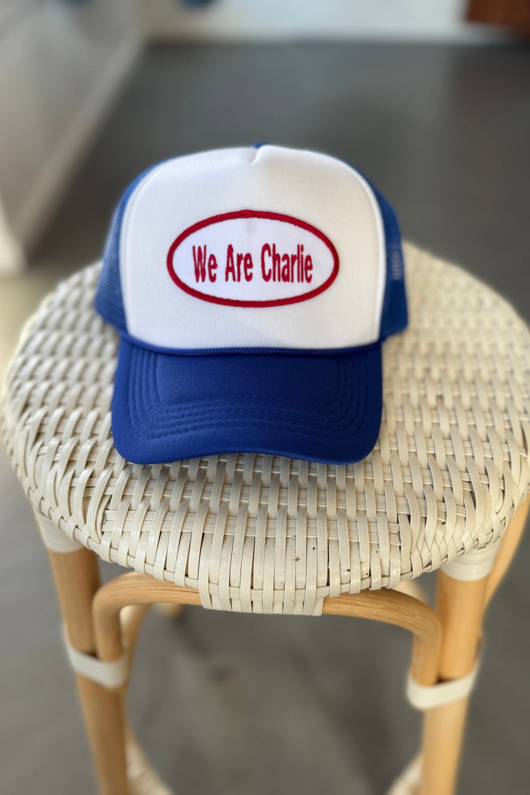 Trucker hat with 'We Are Charlie' text on a wicker stool