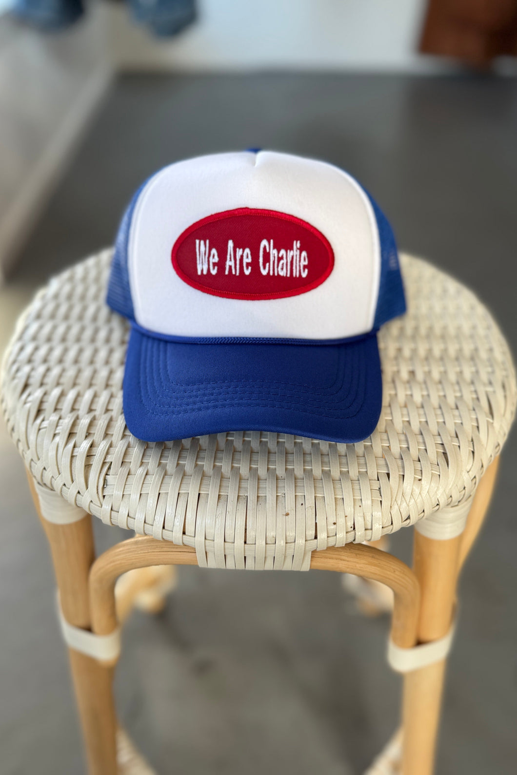 Trucker hat with 'We Are Charlie' on a wicker stool