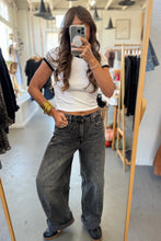 Load image into Gallery viewer, Person taking a mirror selfie wearing a white crop top and dark jeans in a clothing store.