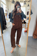 Load image into Gallery viewer, Person wearing brown overalls taking a mirror selfie in a store.