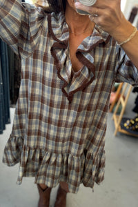 Person wearing a plaid dress with ruffled details, taking a mirror selfie.
