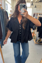 Load image into Gallery viewer, Woman taking a mirror selfie wearing a black top and blue jeans in a clothing store.