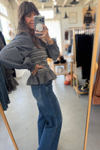 Load image into Gallery viewer, Person taking a mirror selfie wearing a plaid top and blue jeans in a clothing store.