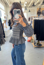 Load image into Gallery viewer, Person taking a mirror selfie wearing a patterned top and jeans in a clothing store.