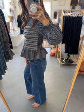 Load image into Gallery viewer, Person wearing a patterned top and blue jeans in a clothing store.