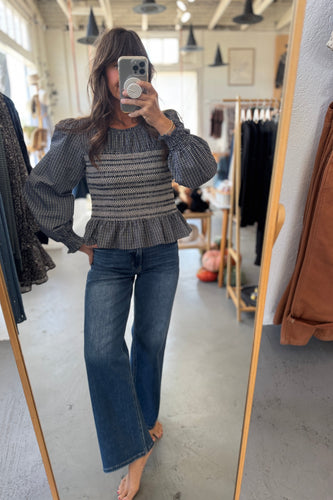 Person wearing a patterned sweater and jeans in a clothing store.