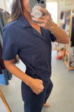 Load image into Gallery viewer, Person wearing a navy blue jumpsuit taking a mirror selfie in a clothing store.