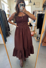 Load image into Gallery viewer, Woman wearing a brown dress in a clothing store.