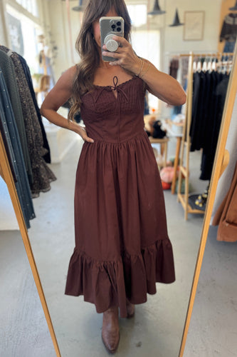 Woman wearing a brown dress in a clothing store.