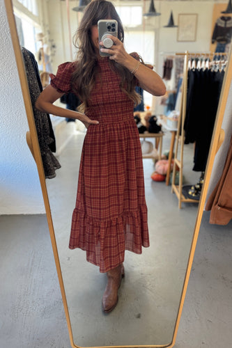 Person wearing a red plaid dress in a clothing store.