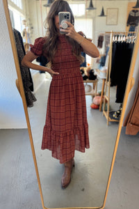Person wearing a red plaid dress in a clothing store.