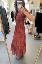 Load image into Gallery viewer, Person wearing a red plaid dress in a clothing store.