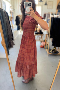 Person wearing a red plaid dress in a clothing store.