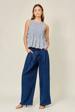Load image into Gallery viewer, Woman wearing a sleeveless checkered top and blue wide-leg pants on a beige background