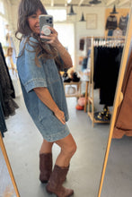 Load image into Gallery viewer, Person taking a mirror selfie wearing a denim dress and brown boots in a clothing store.
