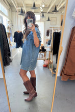 Load image into Gallery viewer, Person wearing a denim dress and brown boots in a clothing store.
