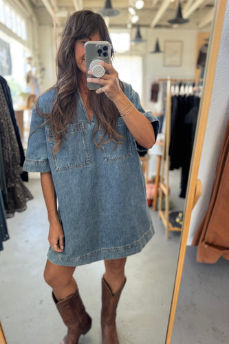 Person wearing a denim dress and brown boots in a clothing store.