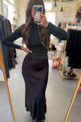 Person wearing a black top and dark skirt in a clothing store.
