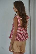 Load image into Gallery viewer, Woman wearing a red and white checkered top and beige shorts against a plain background