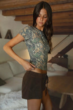 Load image into Gallery viewer, Woman wearing a camouflage shirt and brown shorts in a living room setting