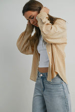 Load image into Gallery viewer, Woman wearing a beige striped cardigan over a white top and blue jeans on a plain background