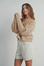 Load image into Gallery viewer, Woman wearing a beige cable knit sweater and light-colored shorts on a plain background