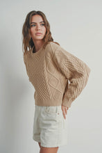 Load image into Gallery viewer, Woman wearing a beige cable knit sweater and light-colored shorts against a plain background